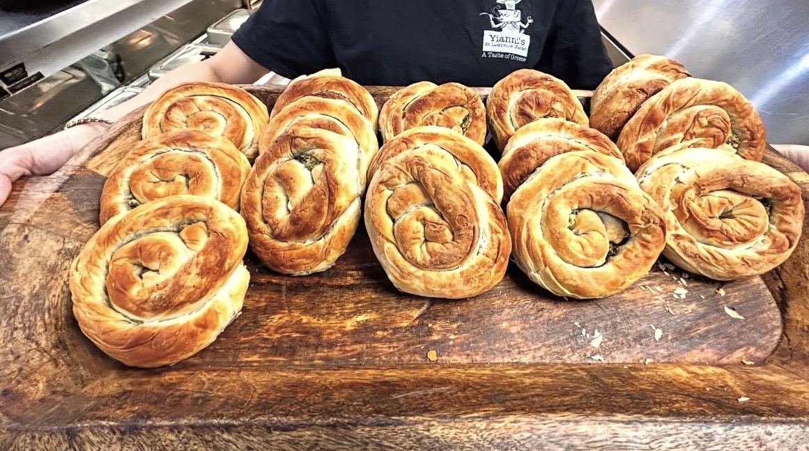 Fresh baked spiral spanakopita pastries on a wooden board